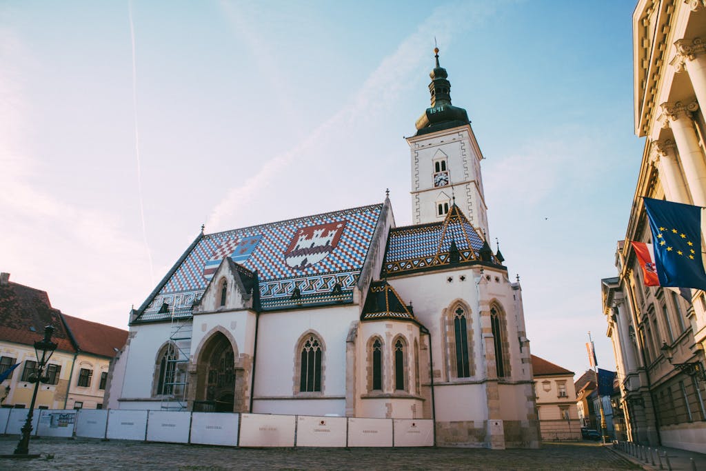 Beautiful view of St. Mark's Church and Town Square in Zagreb, Croatia under a clear blue sky.